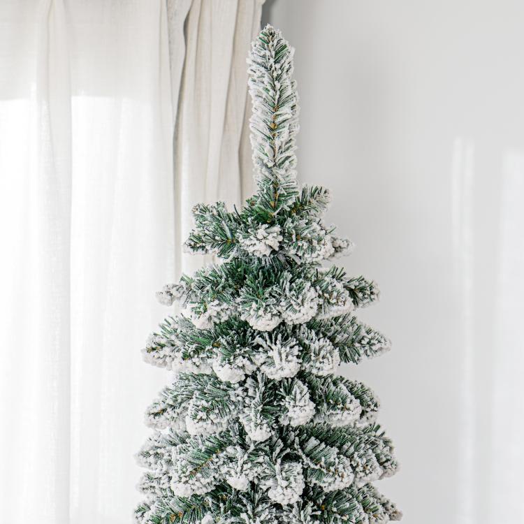 Snow-frosted artificial Christmas tree with dense green needles and snowy tips