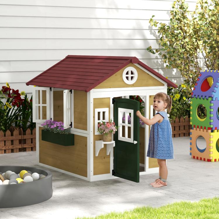 Wooden kids playhouse with green door, windows, and red roof on patio