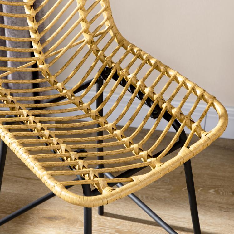 Close-up of woven rattan seat and curved back on a black steel bar stool frame