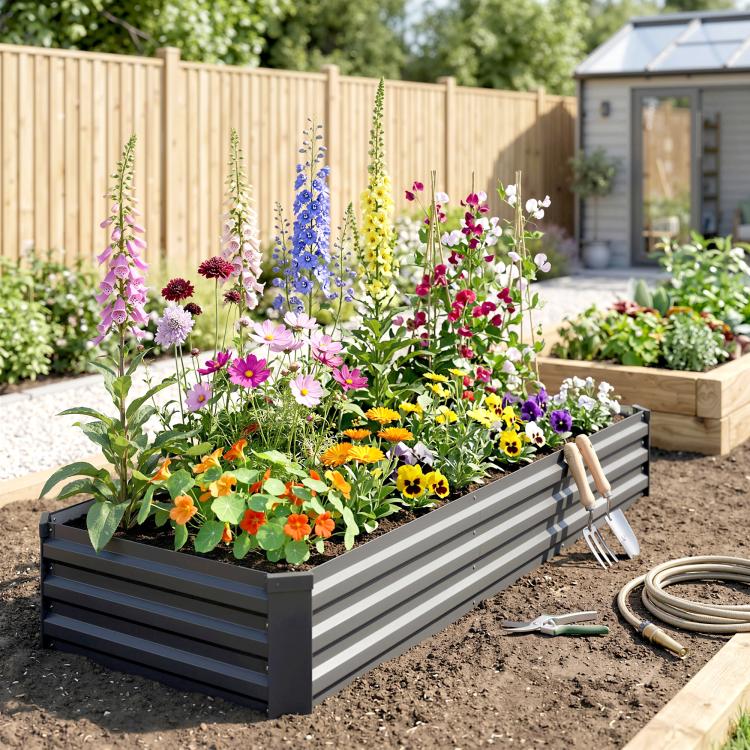 Dark gray raised galvanized garden bed lined with blooming flowers and greenery