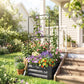 Dark gray raised garden bed with metal trellis and colorful flowers in soil