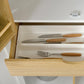 Kitchen pantry storage cabinet drawer open with wooden handle; cutlery stored inside