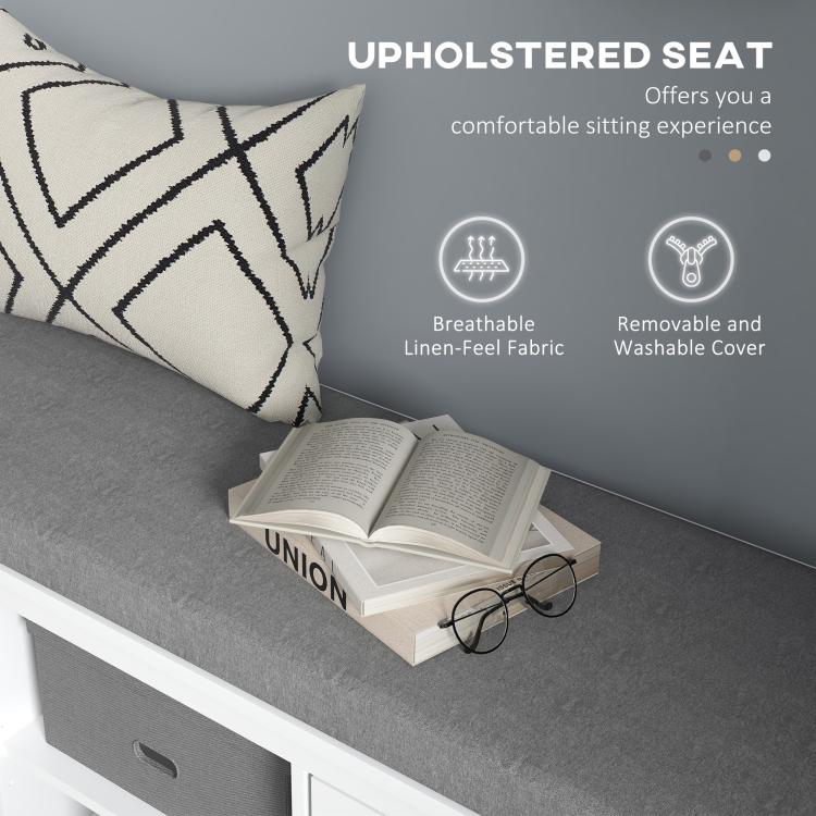Gray upholstered seat on white shoe storage bench with patterned pillows and removable cover