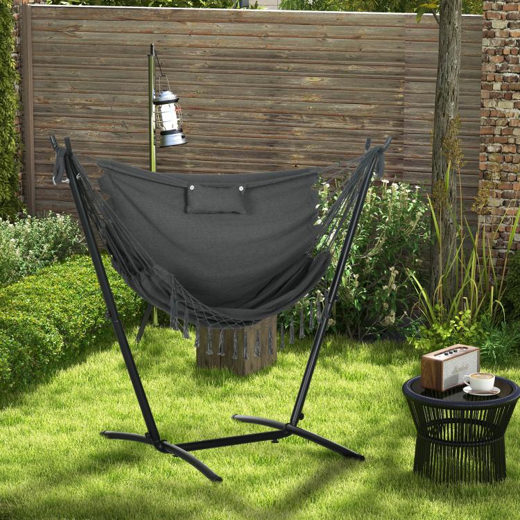 Dark gray hammock chair with headrest pillow and rope fringe on freestanding stand
