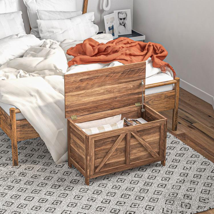 Lift-top storage chest with lid open, holding folded linens inside, brown wood grain