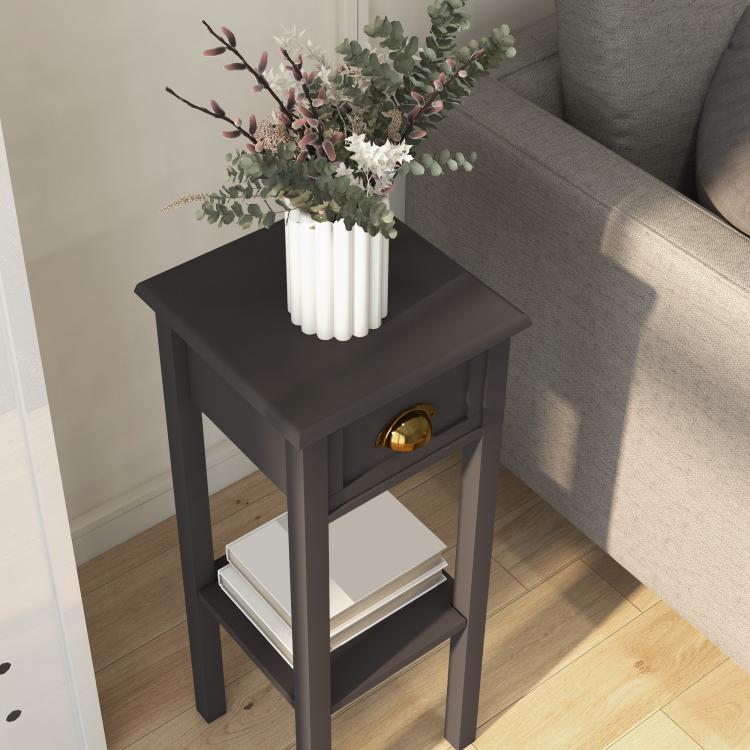 Charcoal end table with drawer and lower shelf holding books and flowers