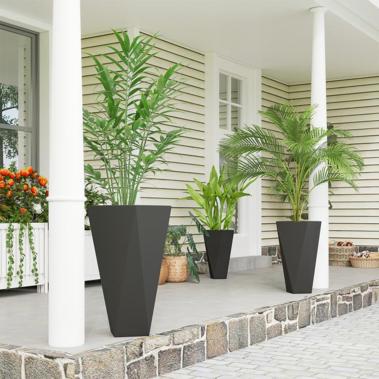 Three tall black planters on outdoor stone steps, each holding a green plant