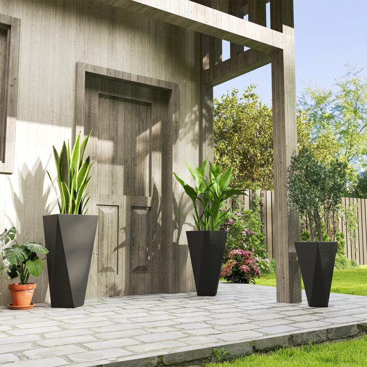Outdoor black tall planters with green plants on a paved patio walkway