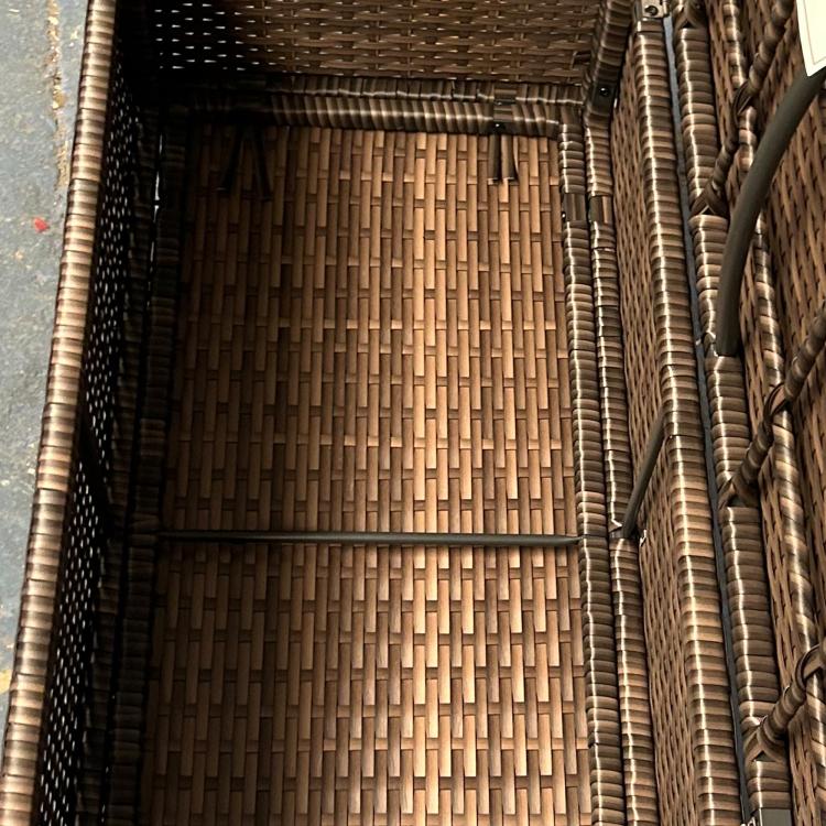 Outdoor storage bench interior with woven wicker base and side walls.