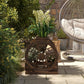 Wooden wagon planter box with wheel frame, holding green plants outdoors on patio