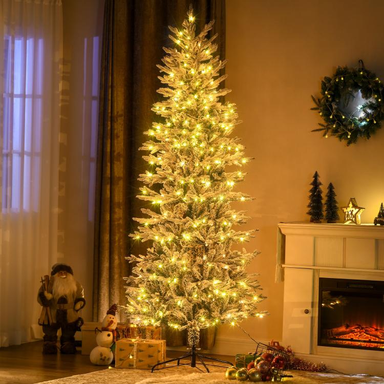 Flocked artificial Christmas tree with warm yellow clear lights, standing on metal stand
