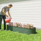 Green metal raised garden bed planter on grass with fresh soil and a watering pour