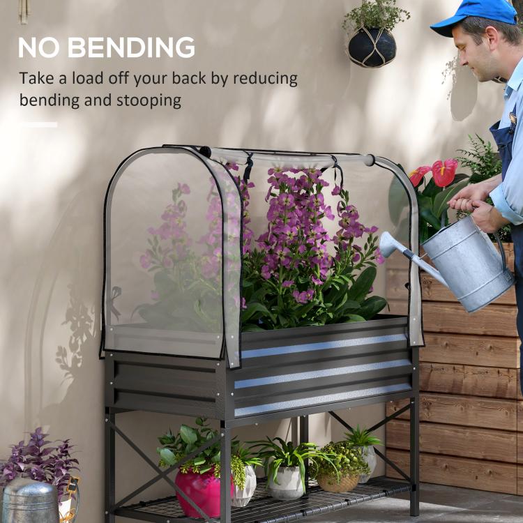 Black raised garden bed planter with clear mesh cover while watering with a can