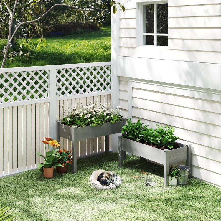 Gray raised garden bed planter set on a patio with small potted greens