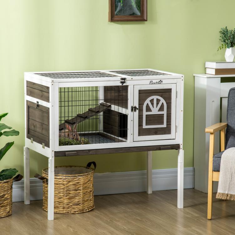 Elevated rabbit hutch with wire panels, front door, and dark ramp; coffee wood sides