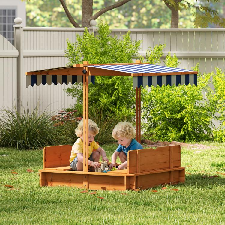 Outdoor wooden kids sandbox with striped canopy and bench seats, children playing