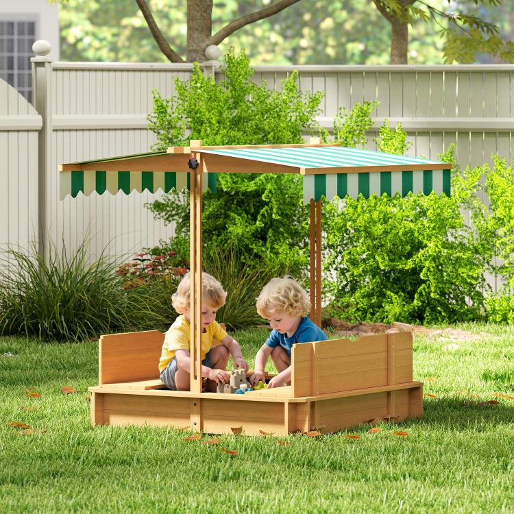Wooden kids sandbox with striped canopy and bench seats, children playing outdoors
