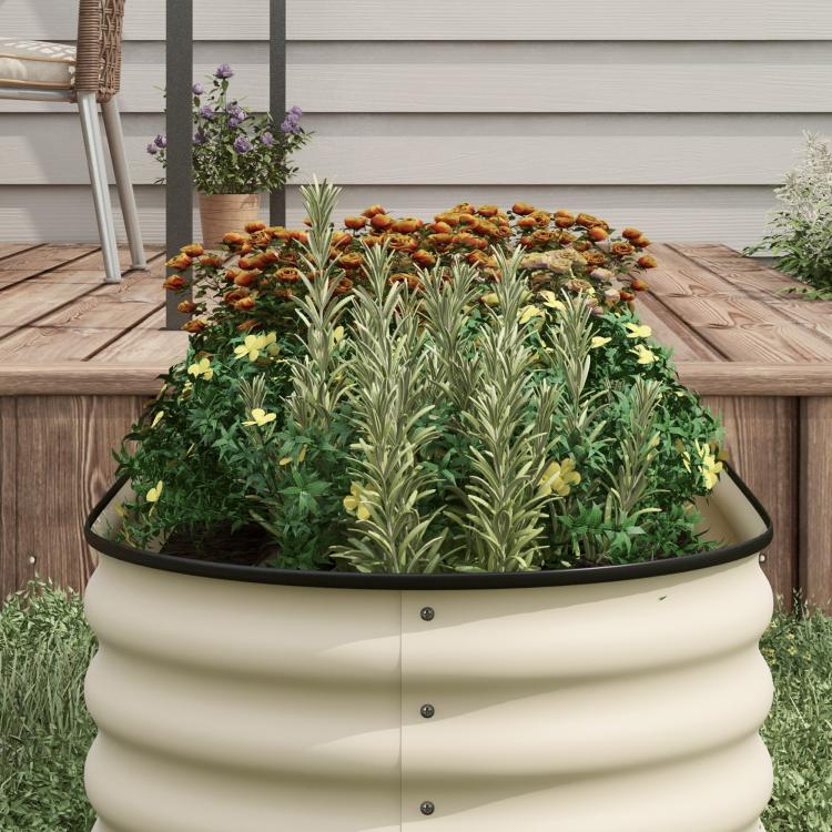 Cream metal raised garden bed with black safety edging, filled with soil and plants