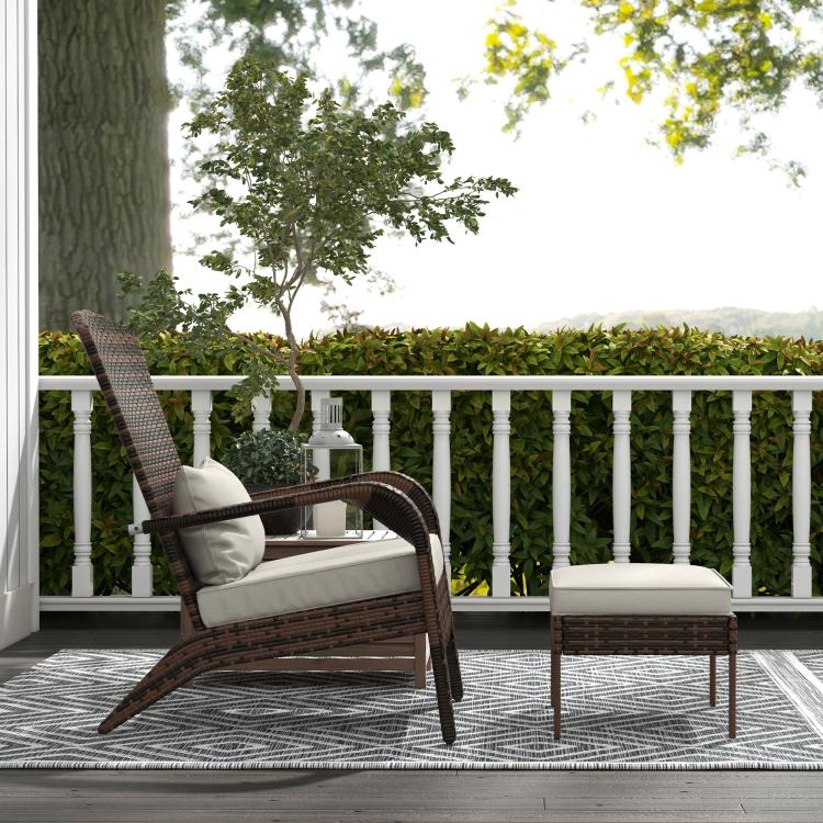Brown wicker armchair with white cushions and matching ottoman on outdoor porch