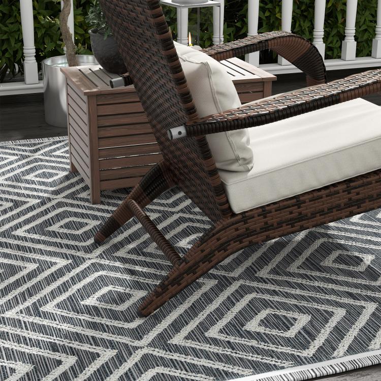 Detail view of brown wicker chair with white cushions and attached ottoman cushion