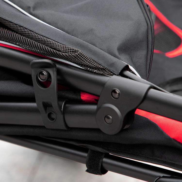 Dog stroller frame latch with red fabric panel and black wheels, close-up