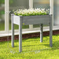 Dark gray raised wooden planter box with planted white flowers and four legs