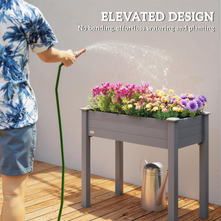 Raised dark gray wooden planter box with colorful flowers, being watered