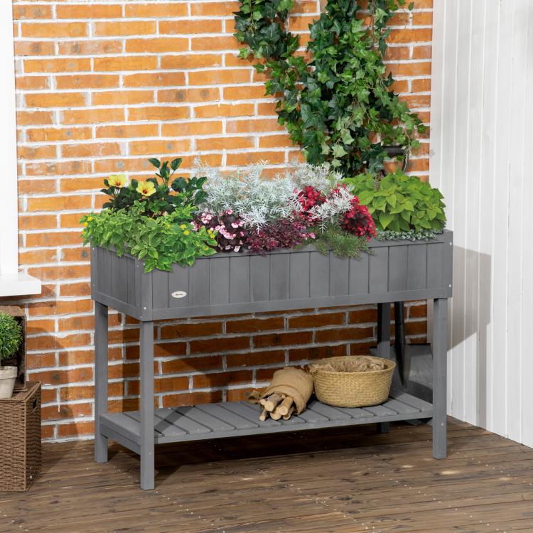 Dark gray raised garden bed with leafy plants and lower storage shelf on legs