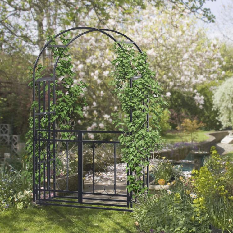 Outdoor grey metal garden arbor arch with open gate and climbing vine frame