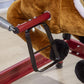 Close-up of red handle and black support bar on plush rocking horse frame