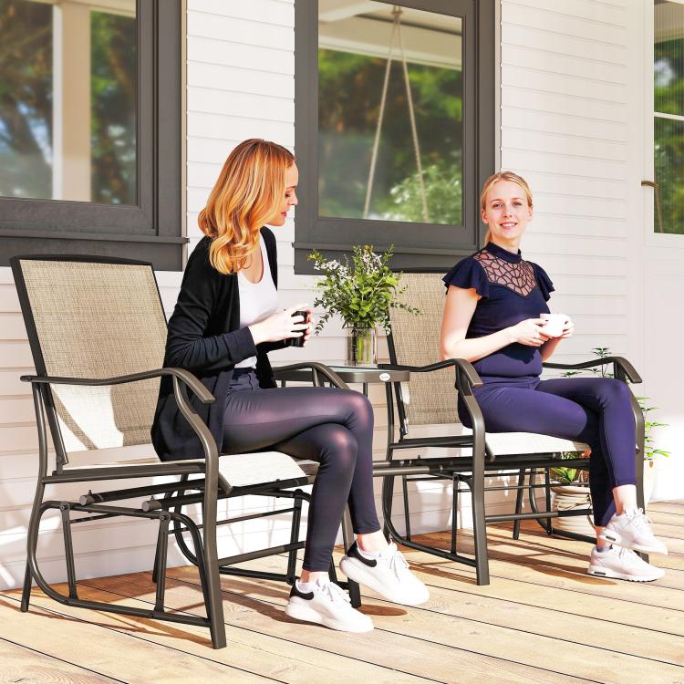 Patio rocking glider chairs with light beige sling fabric and dark armrests, small side table between