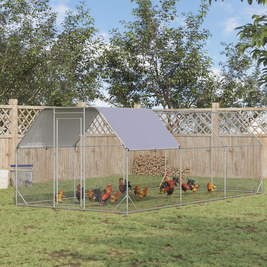 Outdoor metal chicken coop run with mesh fencing and gray roof cover in a yard