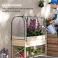 Raised garden bed with clear cover, cream frame, and gardener watering plants