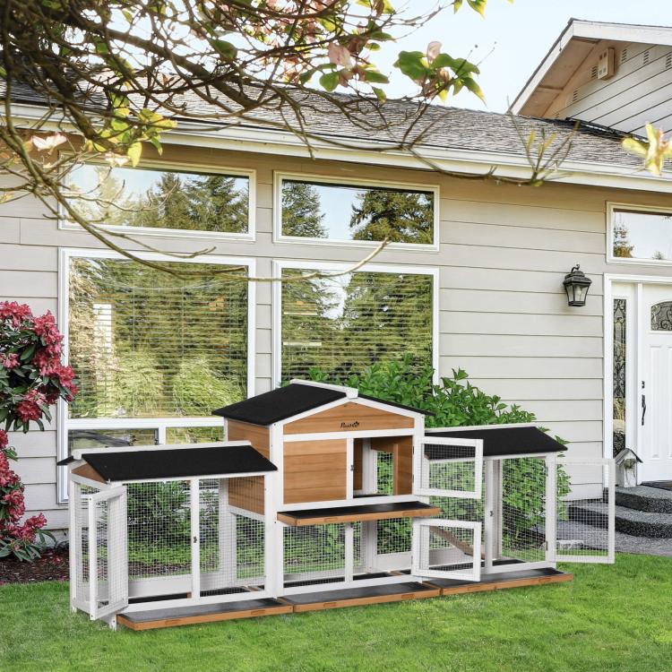 White and wood rabbit hutch with black roof panels, side runs, and central entry door