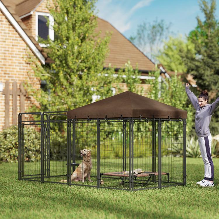 Outdoor dog kennel with brown canopy roof and steel mesh panels, person guiding a dog