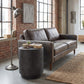 Dark gray cylindrical accent side table with concrete-look finish beside a sofa