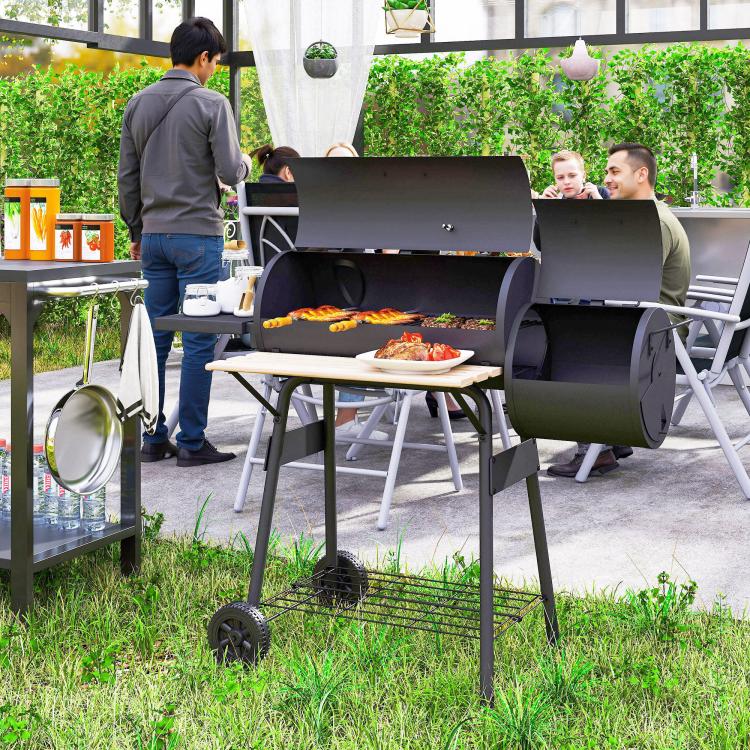 Charcoal BBQ grill and smoker combo on wheels, open lid with food on grates