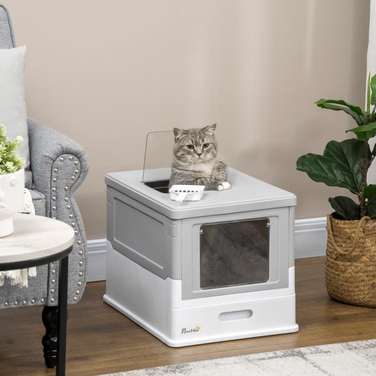 Gray and white enclosed cat litter box on floor with front window opening and cat