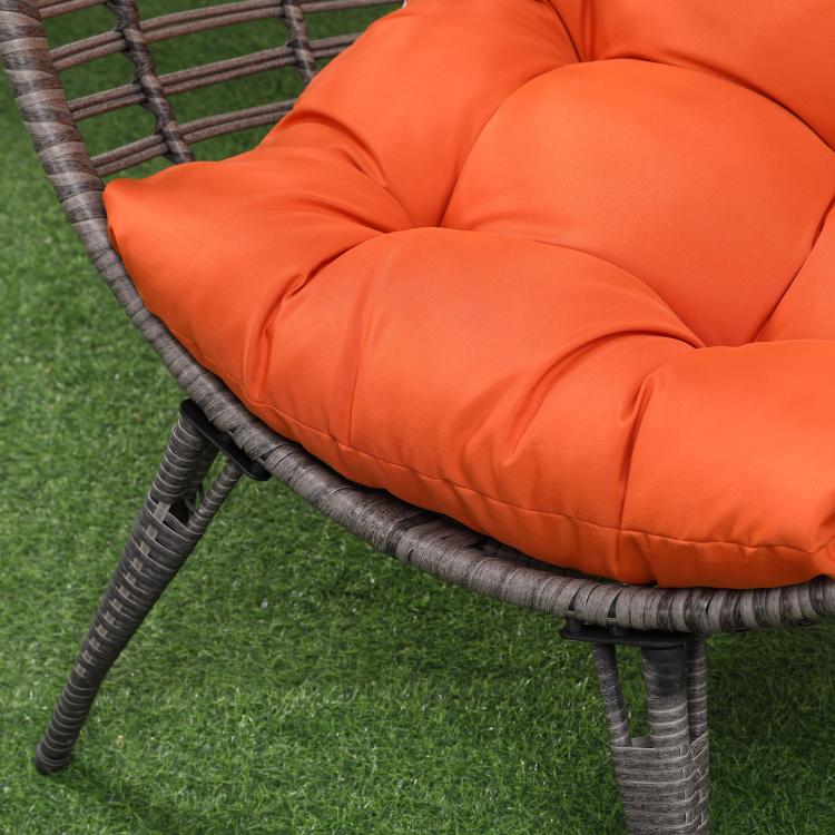 Close-up of orange padded egg chair seat cushion on dark wicker base frame
