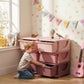 Pink 3-tier kids storage organizer with six drawer bins beside children’s toys