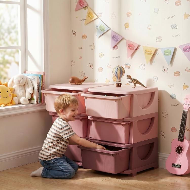 Pink 3-tier kids storage organizer with six drawer bins beside children’s toys
