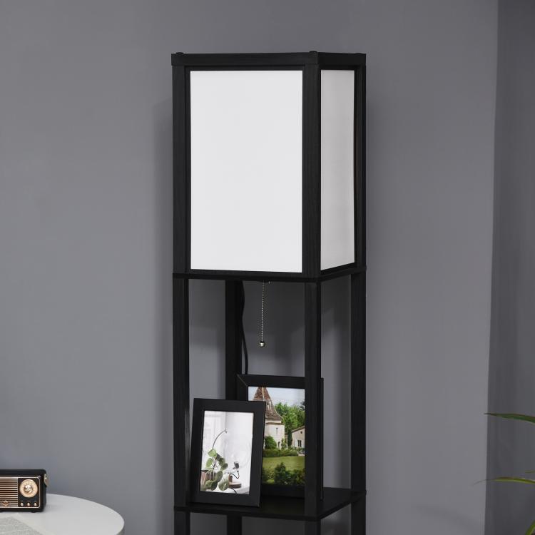Black shelf floor lamp with large upper light panel and lower open cubby with photo frame