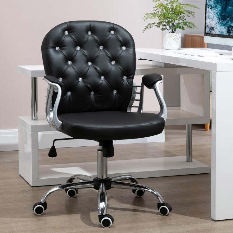 Black tufted swivel desk chair with padded armrests and chrome base on office floor