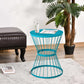 Blue hourglass side table with round top holding a clear glass