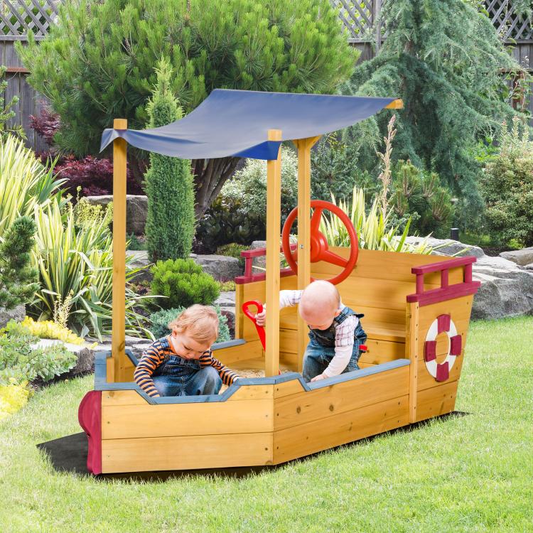 Kids wooden sandbox with blue canopy, bench seats, and red lifebuoy wheel outdoors