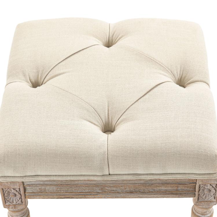 Beige upholstered ottoman footrest with tufted seat and rounded top edges