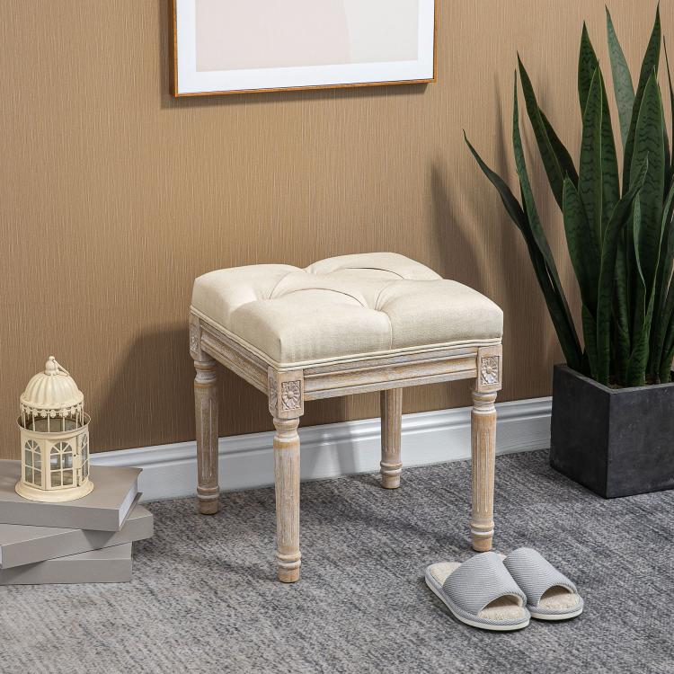 Beige ottoman bench with tufted top cushion and distressed carved wooden legs