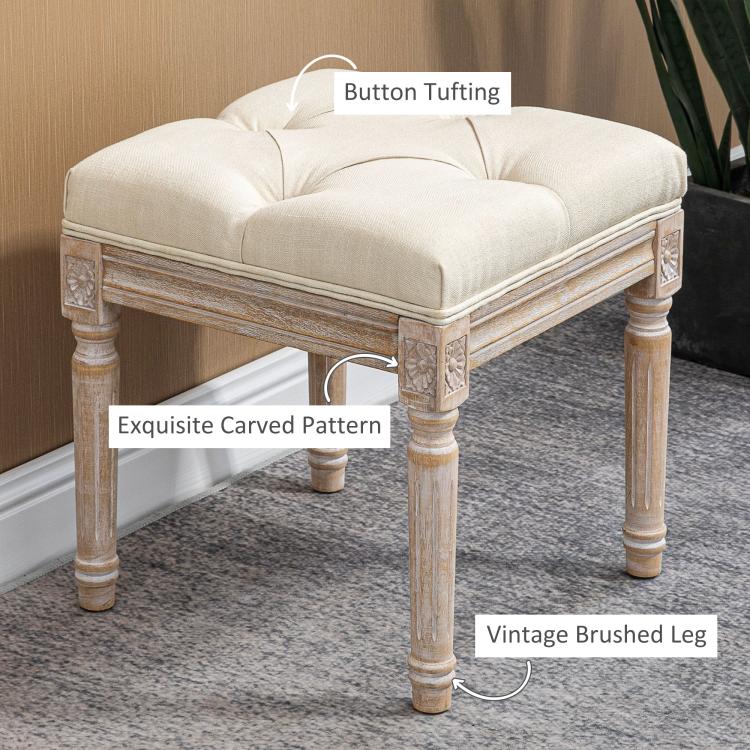 Beige button-tufted ottoman bench with carved leg details and cushioned seat
