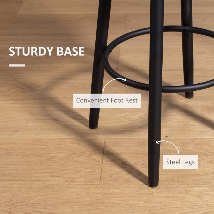 Black steel bar stool legs with circular footrest under a cream upholstered seat