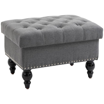 Gray storage ottoman with button-tufted lid, dark studded trim, and turned legs